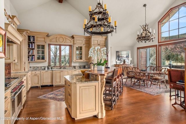 kitchen featuring glass insert cabinets, a notable chandelier, cream cabinetry, and dark wood-style flooring