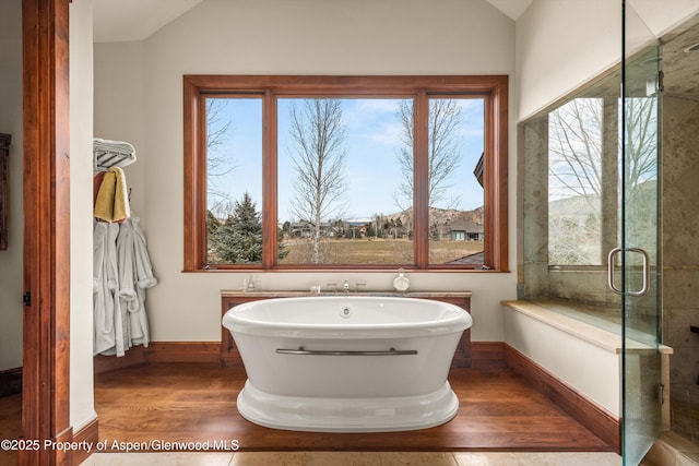 bathroom featuring a shower with door, a freestanding tub, lofted ceiling, and wood finished floors