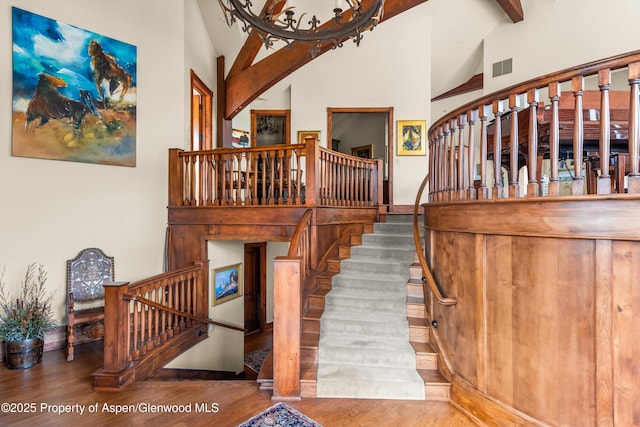 stairs featuring visible vents, high vaulted ceiling, beamed ceiling, and wood finished floors