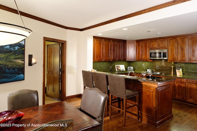 kitchen with dark hardwood / wood-style floors, backsplash, a breakfast bar area, a kitchen island, and ornamental molding