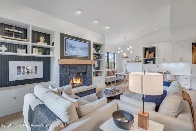 living room with light hardwood / wood-style flooring, vaulted ceiling, built in shelves, a fireplace, and a notable chandelier