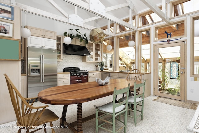 kitchen featuring a healthy amount of sunlight, under cabinet range hood, range with two ovens, and stainless steel fridge