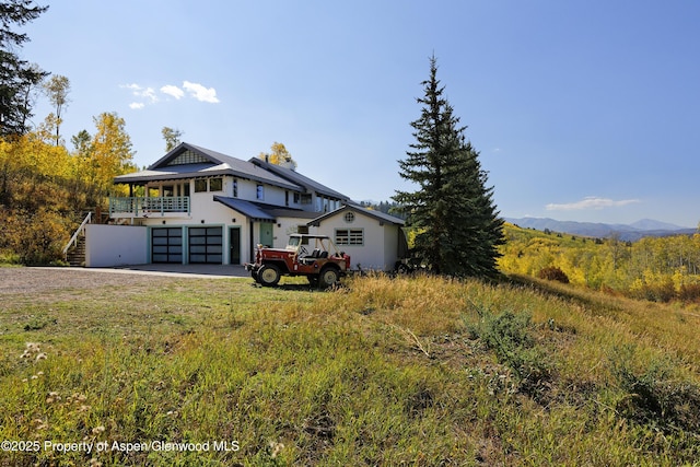 rear view of property with a garage, stairway, and driveway