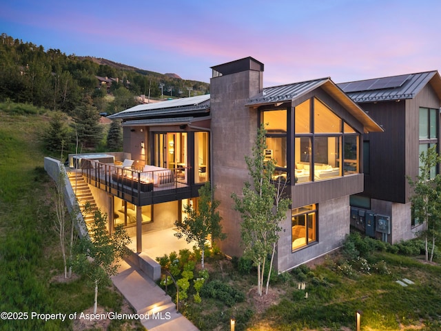 411 Wood Rd Unit 10, Snowmass Village, CO 81615 - back of house at dusk featuring roof mounted solar panels, a standing seam roof, a metal roof, and a patio