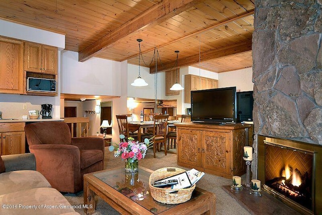 carpeted living area with a sink, wooden ceiling, a fireplace, and beam ceiling