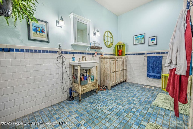 bathroom with a sink, tile walls, and wainscoting