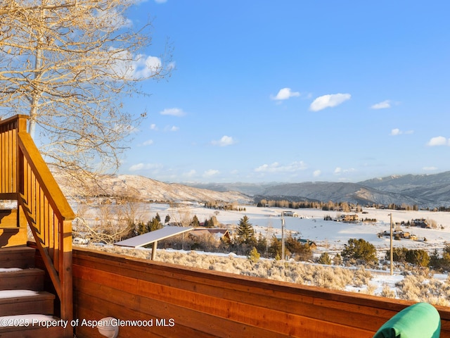 snow covered deck with a mountain view