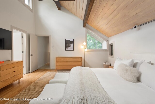 bedroom with vaulted ceiling with beams, wood ceiling, and light wood-type flooring