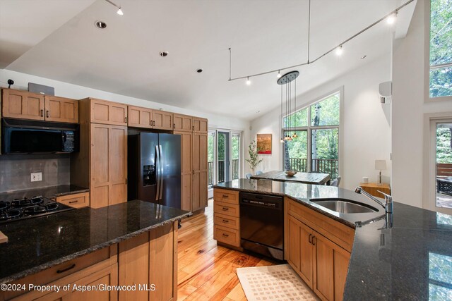 kitchen with black appliances, dark stone countertops, sink, and hanging light fixtures