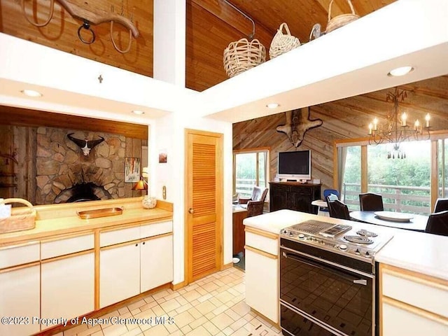 kitchen featuring a high ceiling, a stone fireplace, range with electric stovetop, wood walls, and decorative light fixtures