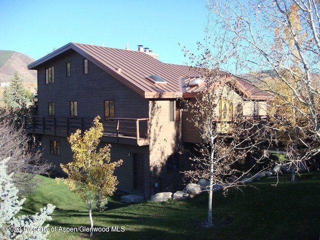 back of property with a mountain view, a yard, and a balcony