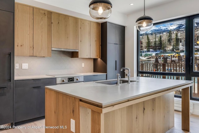 kitchen with pendant lighting, tasteful backsplash, a kitchen island with sink, and sink