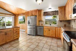 8984 County Road 300, Parachute, CO 81635 - kitchen with appliances with stainless steel finishes, healthy amount of natural light, decorative backsplash, brown cabinets, and vaulted ceiling