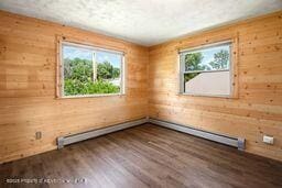 8984 County Road 300, Parachute, CO 81635 - unfurnished room with healthy amount of natural light, wood walls, wood finished floors, and a baseboard radiator