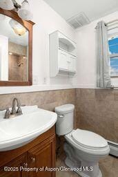 8984 County Road 300, Parachute, CO 81635 - bathroom with vanity, tile walls, wainscoting, and baseboard heating