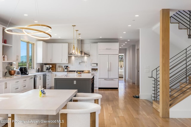 577 Fox Run Dr, Carbondale, CO 81623 - kitchen featuring paneled built in refrigerator, wall chimney range hood, a center island, tasteful backsplash, and white cabinets
