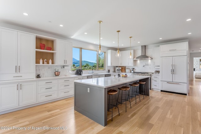 577 Fox Run Dr, Carbondale, CO 81623 - kitchen featuring wall chimney exhaust hood, paneled built in refrigerator, tasteful backsplash, a breakfast bar area, and white cabinetry