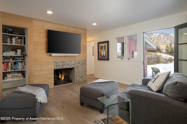 living room with a tile fireplace, baseboards, recessed lighting, and wood finished floors