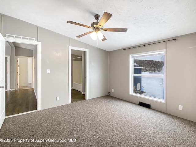 unfurnished bedroom featuring ensuite bath, vaulted ceiling, ceiling fan, a textured ceiling, and carpet floors