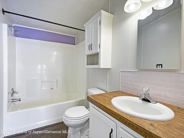 full bathroom featuring shower / bathing tub combination, a textured ceiling, toilet, decorative backsplash, and vanity