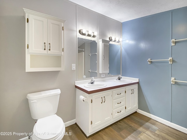 bathroom featuring hardwood / wood-style flooring, vanity, toilet, and a textured ceiling