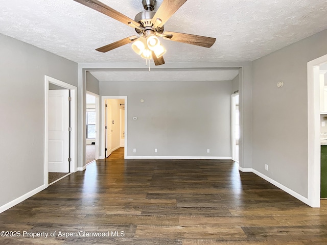 empty room featuring a textured ceiling, ceiling fan, and dark wood-type flooring