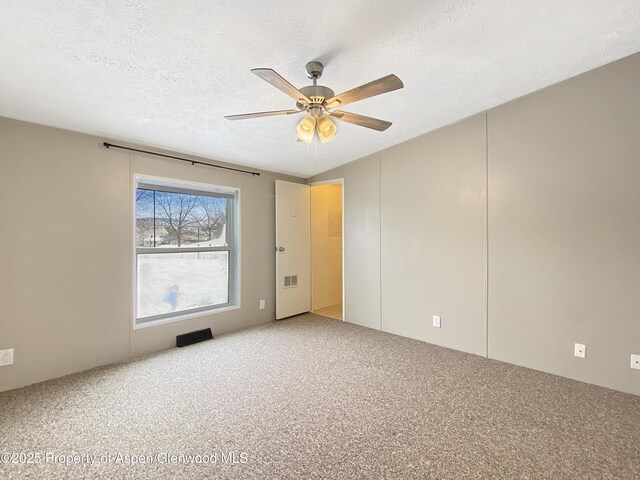 carpeted empty room featuring ceiling fan and a textured ceiling