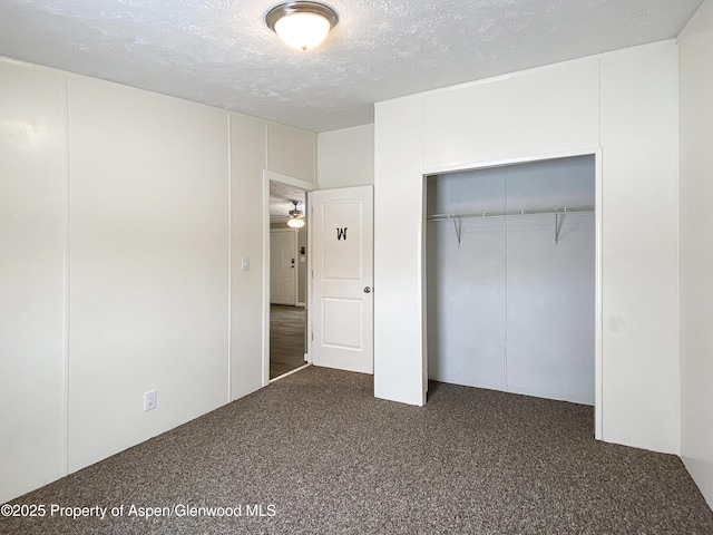 unfurnished bedroom featuring a closet, a textured ceiling, and dark colored carpet