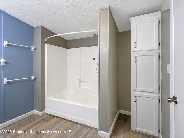 bathroom with wood-type flooring, a textured ceiling, and shower / tub combination