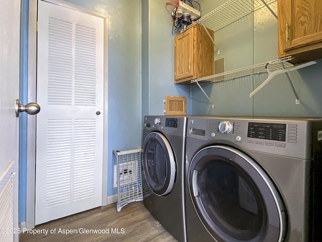 washroom with separate washer and dryer, dark hardwood / wood-style flooring, and cabinets