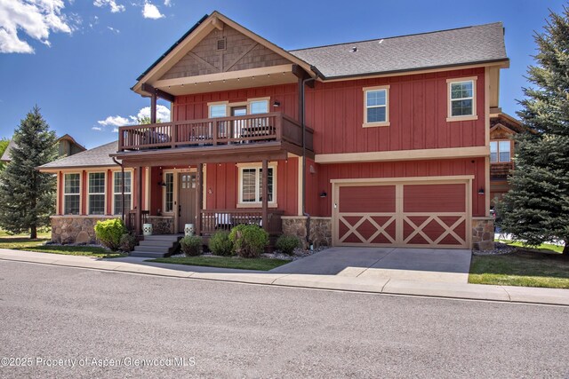 249 Whitehorse Dr, New Castle, CO 81647 - view of front of property with stone siding, a balcony, a shingled roof, covered porch, and driveway