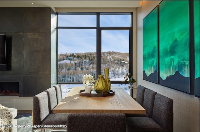 dining room with a mountain view, a wall of windows, and a tiled fireplace