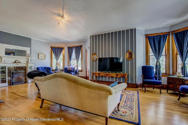 living room with a fireplace, a healthy amount of sunlight, a textured ceiling, and hardwood / wood-style flooring