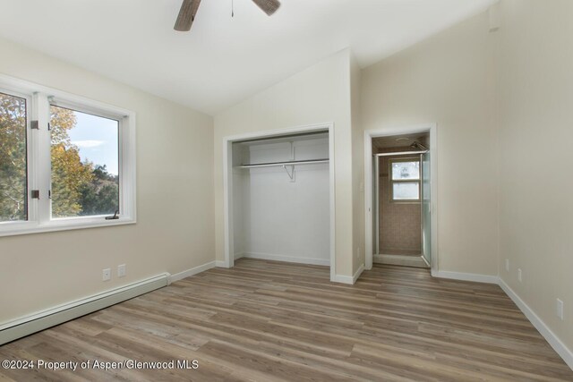 unfurnished bedroom featuring ceiling fan, a baseboard radiator, hardwood / wood-style floors, vaulted ceiling, and a closet