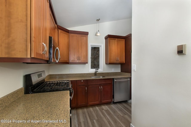 kitchen featuring pendant lighting, lofted ceiling, sink, appliances with stainless steel finishes, and light stone counters