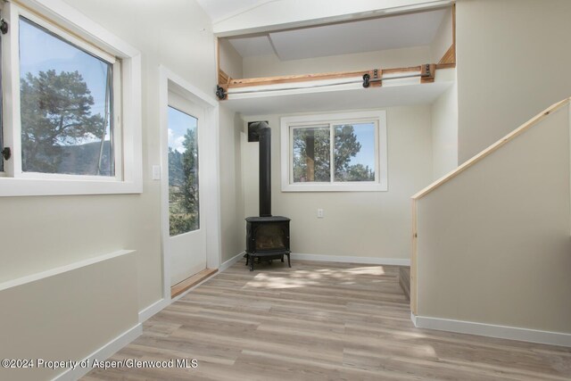 entrance foyer featuring light wood-type flooring and a wood stove