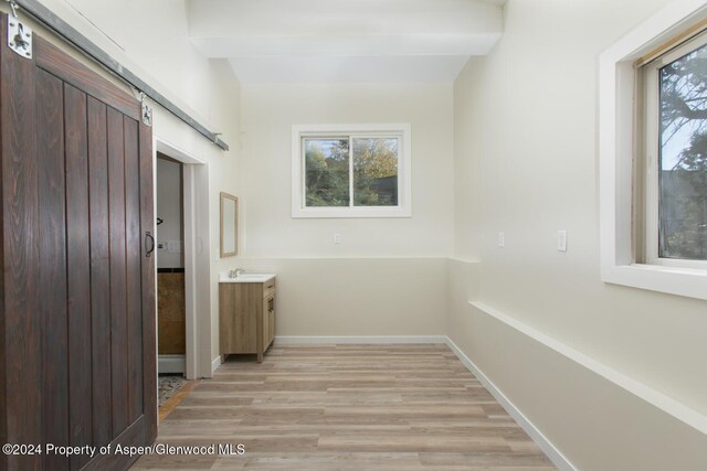 hallway with beam ceiling, a barn door, and a wealth of natural light