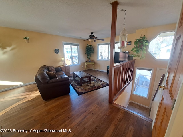 living room with ceiling fan, dark wood-type flooring, and a textured ceiling