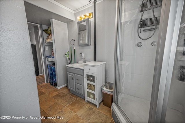 bathroom with crown molding, a stall shower, vanity, and stone finish floor