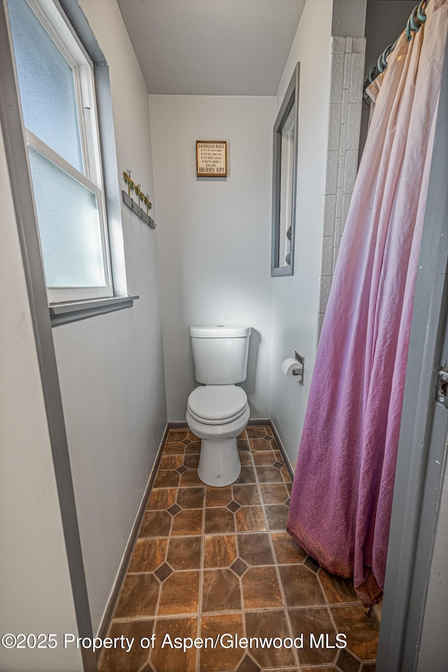 full bath featuring a shower with curtain, toilet, and baseboards