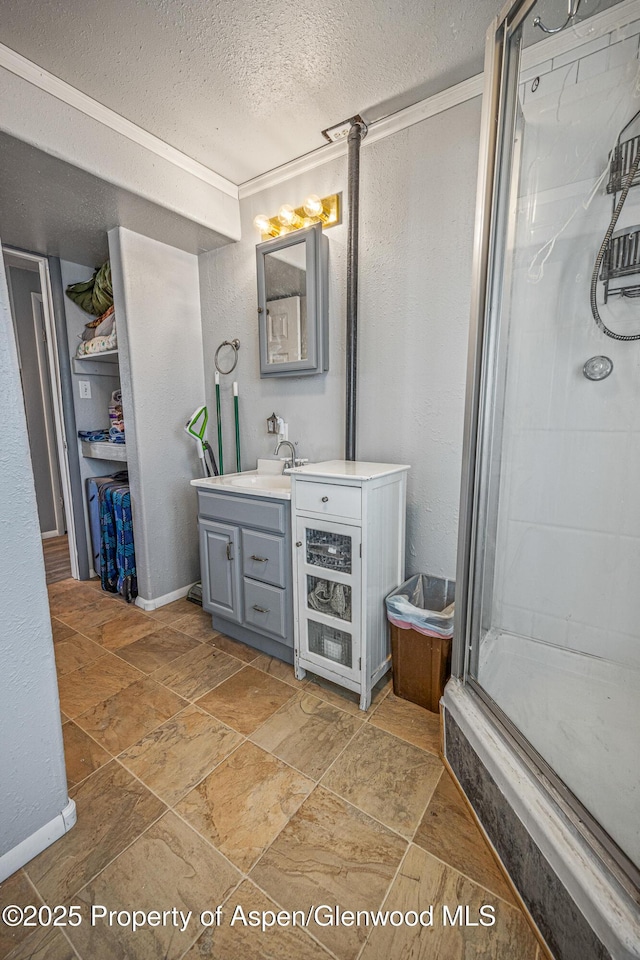 bathroom with stone finish floor, a textured ceiling, a shower stall, vanity, and a textured wall