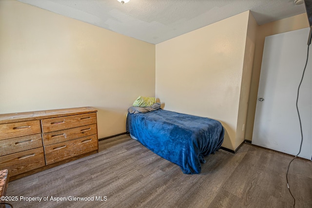 bedroom with wood finished floors, baseboards, and a textured ceiling