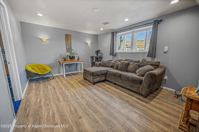 living area with recessed lighting, light wood-style floors, visible vents, and baseboards