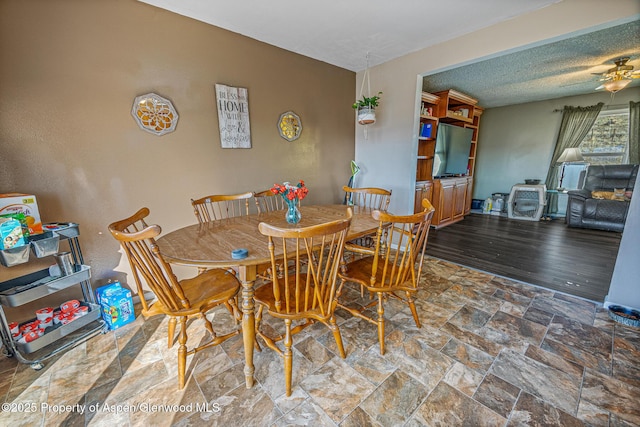 dining room with stone finish floor, a ceiling fan, and a textured ceiling