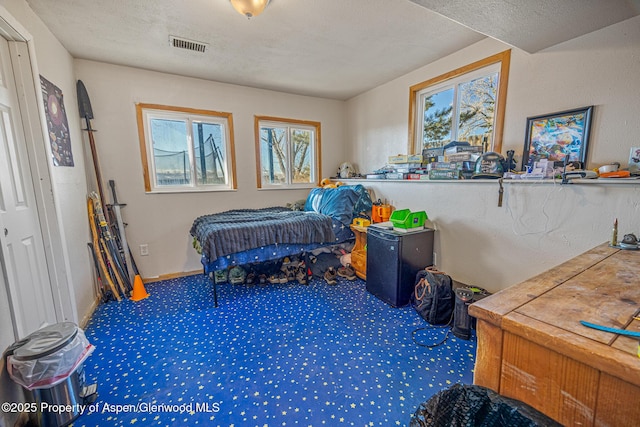 bedroom featuring visible vents, a textured ceiling, and carpet