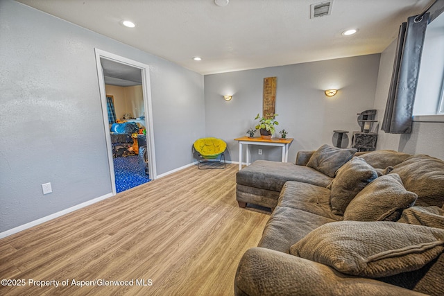 living area with visible vents, wood finished floors, recessed lighting, baseboards, and a textured wall