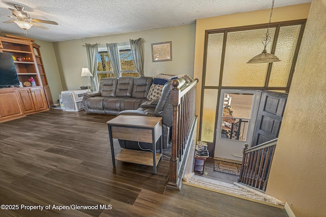 living room with dark wood-type flooring, a ceiling fan, and a textured ceiling