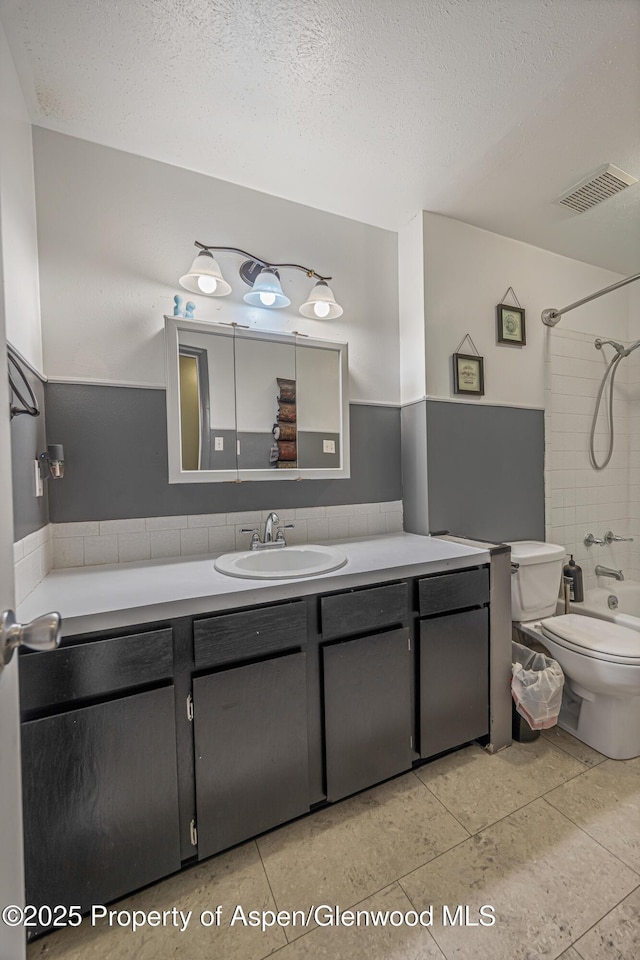 bathroom featuring visible vents, toilet, vanity, shower / bath combination, and a textured ceiling