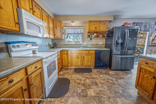 kitchen with a sink, brown cabinetry, stone finish floor, white appliances, and open shelves