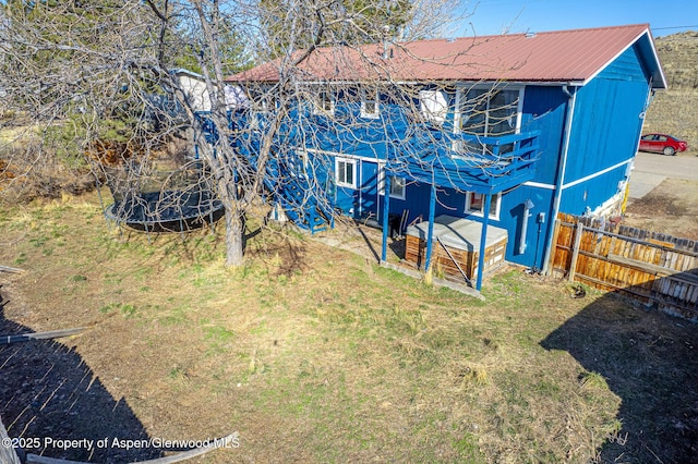 back of property with fence, a lawn, and metal roof